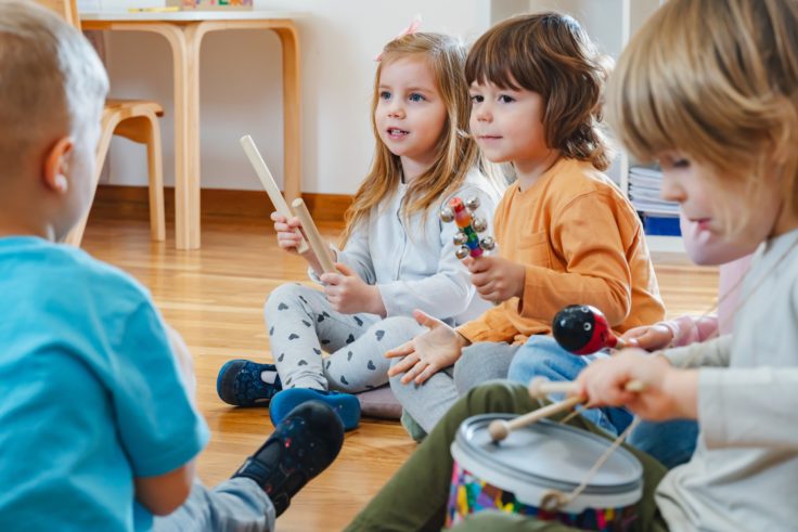 Fire børnehavebørn spiller på instrumenter