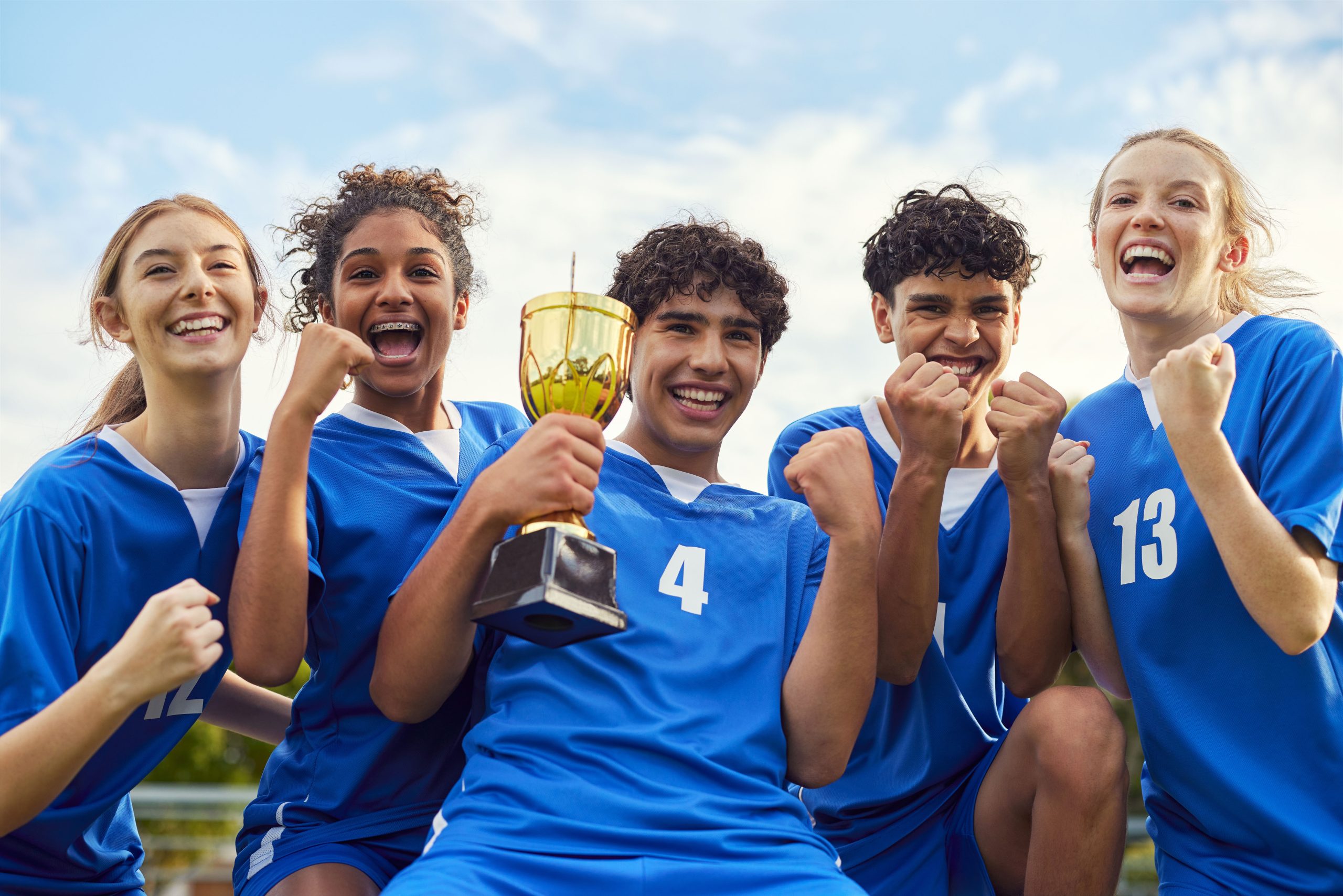 Glade teenagere i sportstøj med guldpokal